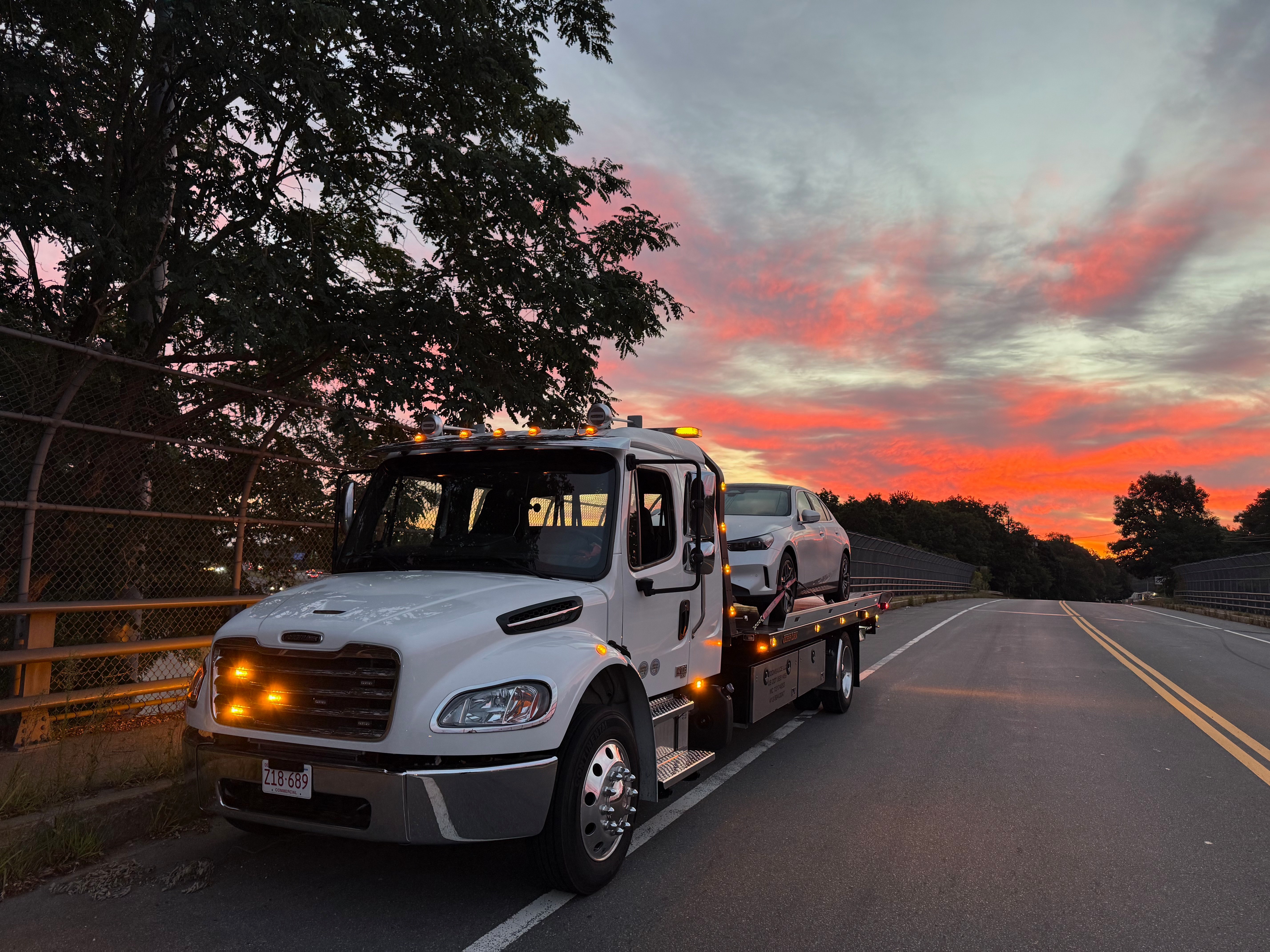 MUSE Towing flatbed transporting a vehicle at sunset